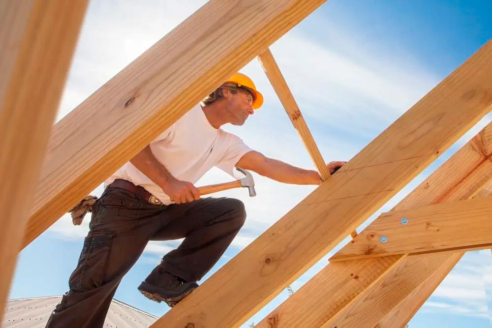 Worker on a wooden beam of a ceiling who knows the best way to price your Roofing Contract