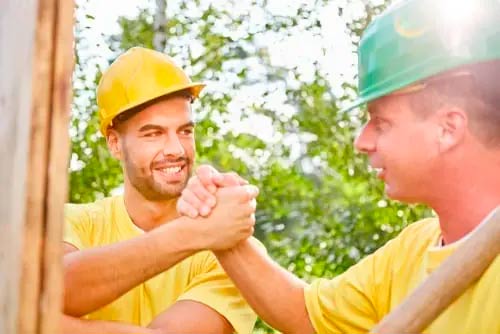 Workers shaking hands because they have tools to improve teamwork on a construction site.