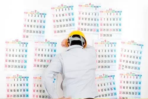 Concerned worker looking at a calendar because he know about the Implications of contractor delays in project delivery.