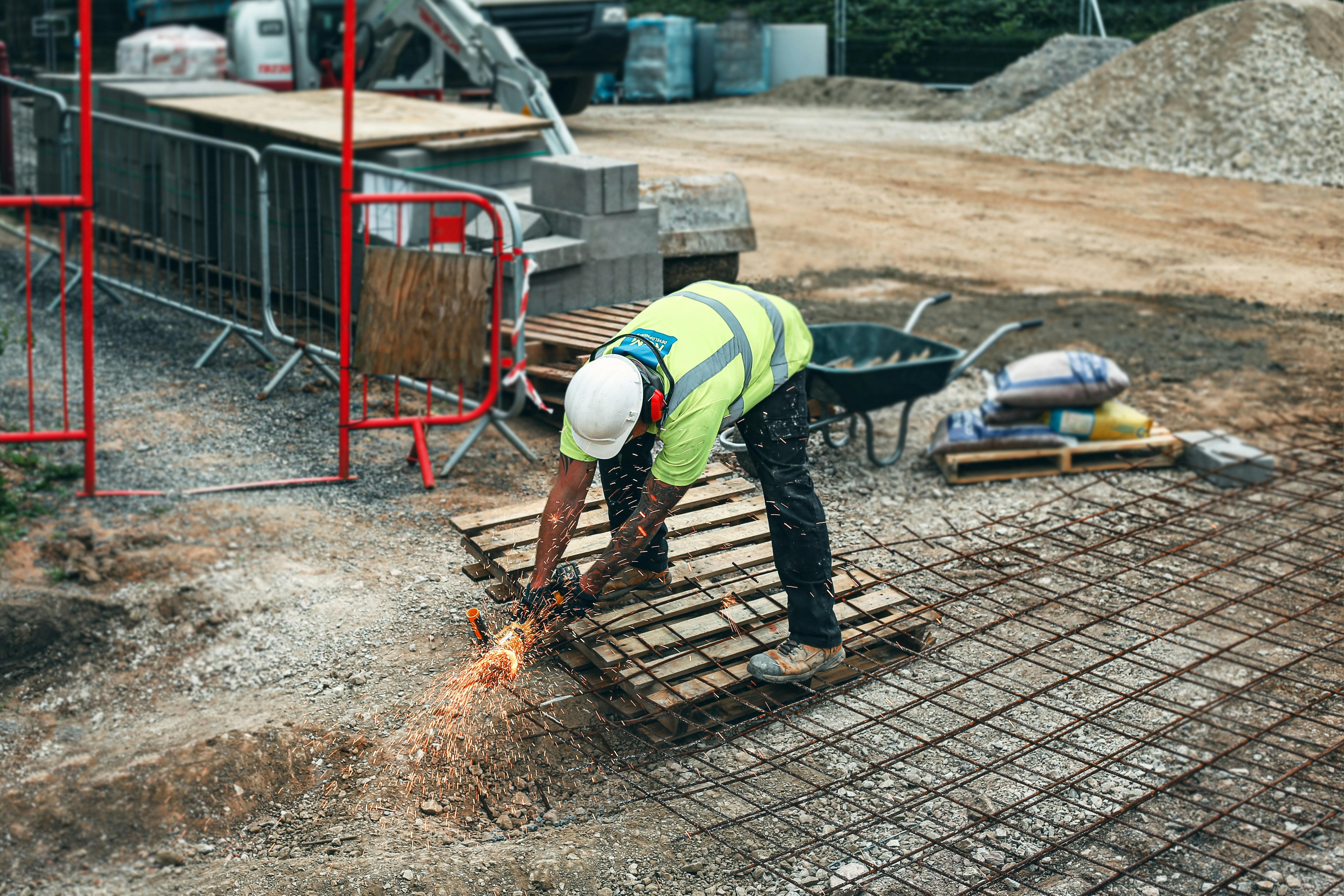 Worker cutting rebar with sparks at construction site, highlighting the need for a Workers Compensation Ghost Policy for contractor jobsite protection.